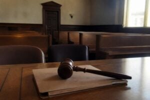 A judge's gavel resting on a closed case file in an empty courtroom, window light