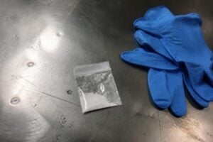 Evidence bag of white powder beside latex gloves