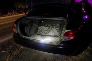 Duffel bag in an open car trunk during a nighttime traffic stop