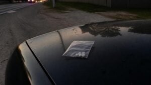 Evidence bag of pills on a car hood during a Houston traffic stop
