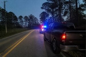 A pickup truck stopped by police on a two-lane road near Humble Texas at dusk, pine trees