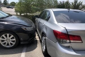 Two cars after a crash in a League City strip center parking lot, bright humid afternoon