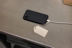 Smartphone plugged in on an evidence table with a tag