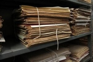 A stack of old court files tied with string on a records room shelf