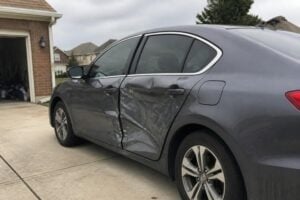 A crumpled car door on a sedan parked in a Sugar Land driveway, overcast day