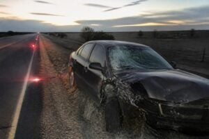 Wrecked sedan on a Texas highway shoulder at dusk